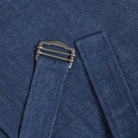 Close-up of denim jeans belt detail with metal clasp engraved with brand name The Female Archetypes.