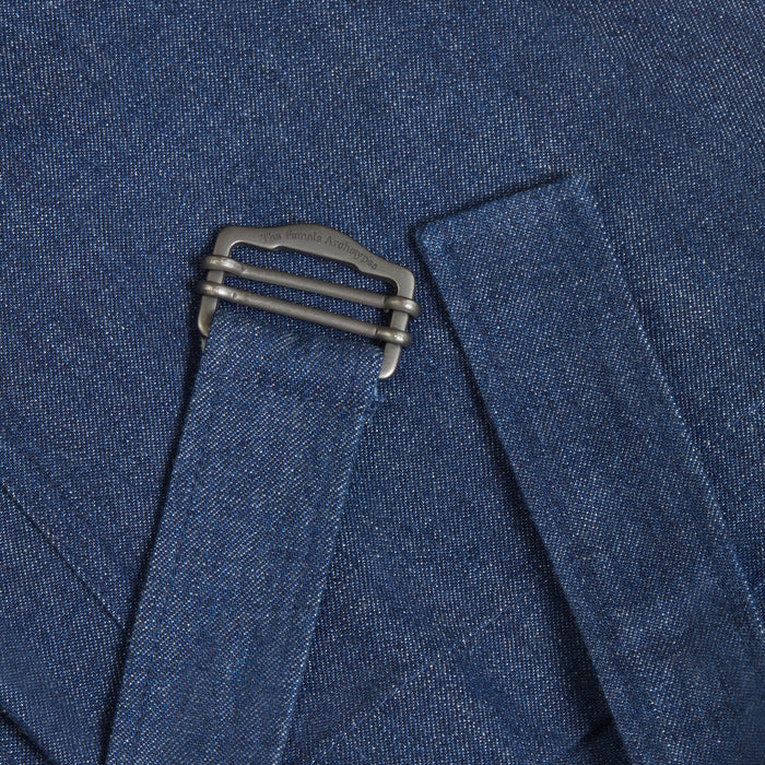 Close-up of denim jeans belt detail with metal clasp engraved with brand name The Female Archetypes.