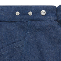 Close-up of denim women's jeans with adjustable waistband with metal buttons & front pocket stitch.