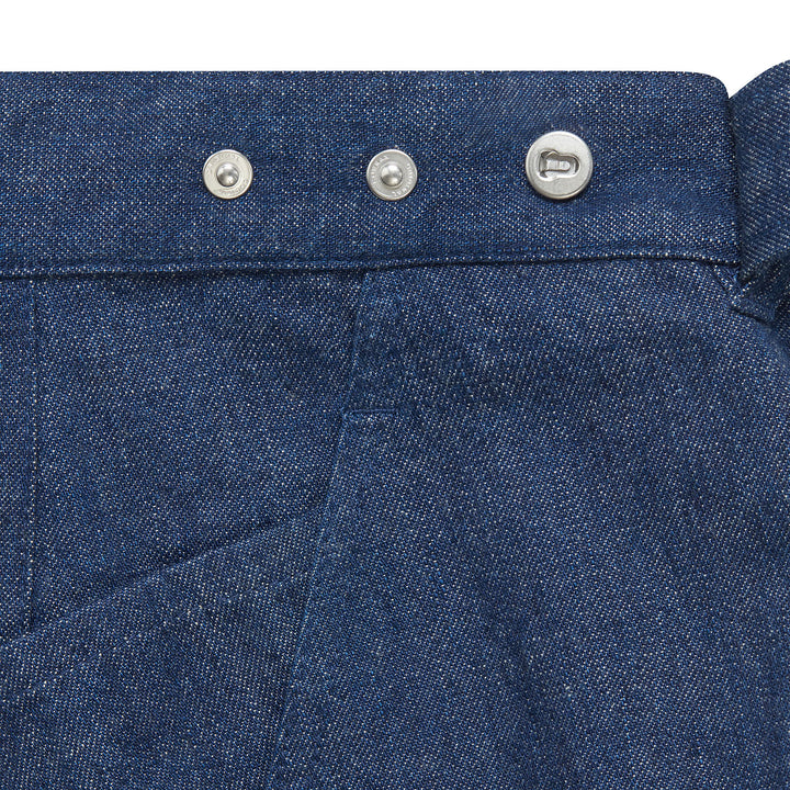 Close-up of denim women's jeans with adjustable waistband with metal buttons & front pocket stitch.
