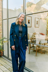 Woman wearing navy blue adjustable size cotton blazer with gold buttons and wide-leg denim jeans.