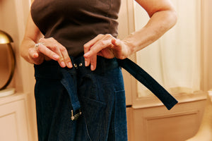 Woman adjusting adjustable wide-leg jeans made in London, designed for a perfect fit, sustainable and timeless fashion.