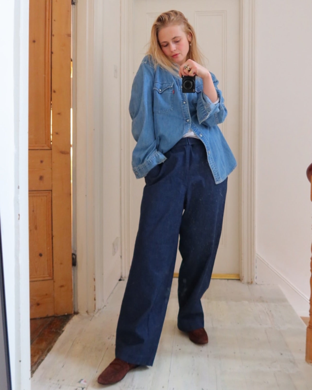 A woman wearing a sustainable denim shirt and our adjustable wide-leg jeans, showing a timeless outfit designed for a perfect fit.