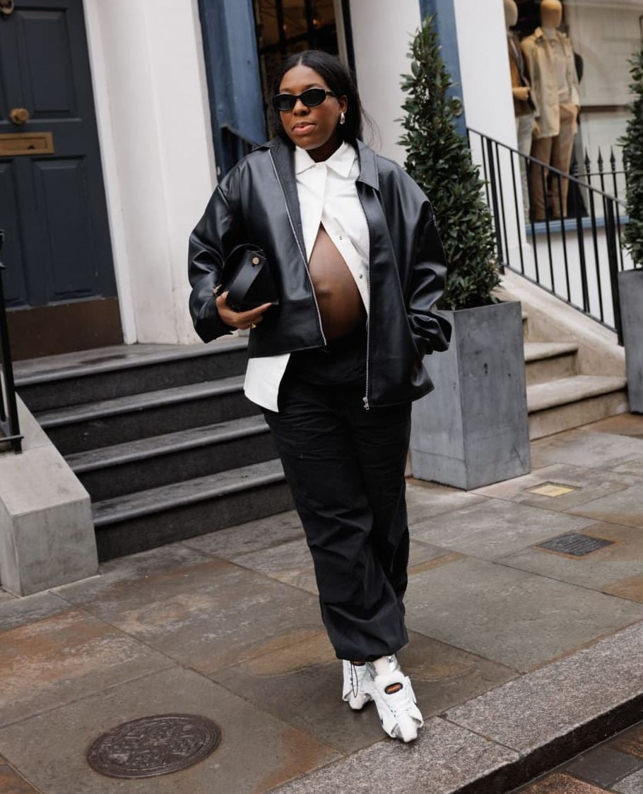 A woman wears a black leather jacket and our sustainable white overshirt, showcasing a timeless and comfortable layered look.